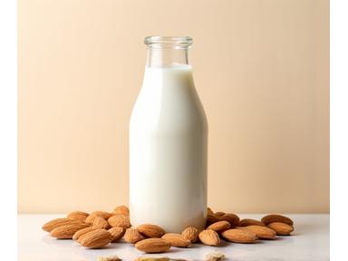 Susu badam buatan sendiri yang lembut di dalam botol kaca dengan badam di sebelahnya.